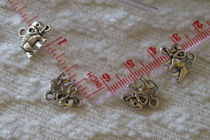 K&ouml;nnte beinhalten: Vier silberne Elefanten-Anh&auml;nger mit filigranen Details. Die Anh&auml;nger sind etwa 2,5 cm gro&szlig; und haben eine &Ouml;se zum Anbringen an Schmuck oder andere Bastelarbeiten.