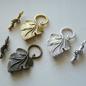 Può includere: Tre set di chiusure decorative in metallo a forma di foglia con un design a vite. Ogni chiusura ha una barra abbinata con un design a grappolo d'uva. Le chiusure sono in oro, argento e bronzo antico.