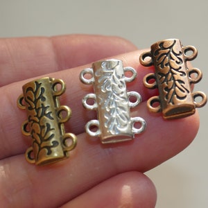 Könnte beinhalten: Drei Metallverschlüsse mit floralem Design. Die Verschlüsse sind in Silber, Gold und Kupfer.