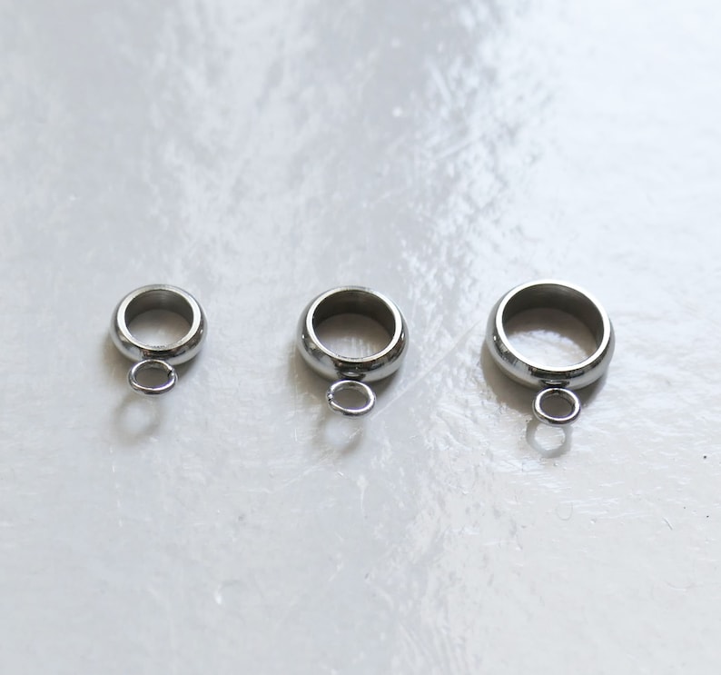 Peut inclure: Trois anneaux de saut en argent avec une petite boucle en bas. Les anneaux sont de tailles diff&eacute;rentes.
