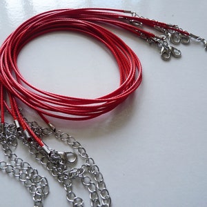 Pode incluir: Um conjunto de colares de cordão vermelho com fechos prateados.