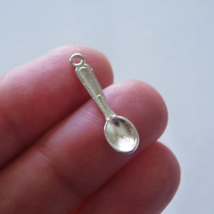 May include: Silver spoon charm with a loop for attaching to a necklace or bracelet. The spoon is about 1 inch long.