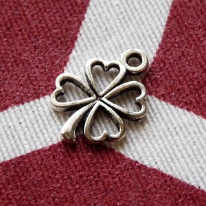 May include: Silver four-leaf clover charm with a loop for attaching to a necklace or bracelet.