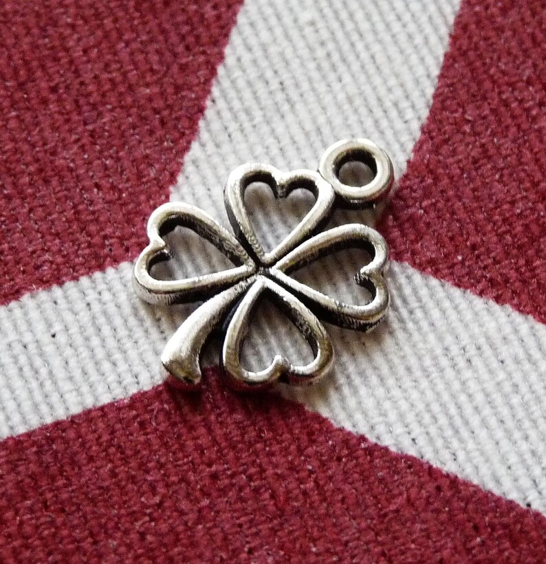 May include: Silver four-leaf clover charm with a loop for attaching to a necklace or bracelet.