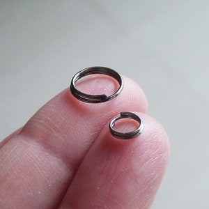 Op de afbeelding: Twee zilveren springringen, waarvan er één groter is dan de andere, worden op een vinger getoond.