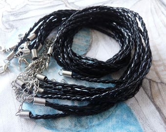 Pode incluir: Um conjunto de cordões de couro trançado preto com fechos de metal prateado. Os cordões estão dispostos em forma circular, com os fechos visíveis nas bordas.