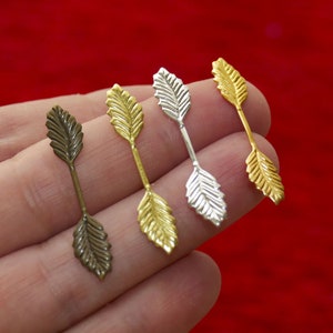 Op de afbeelding: Vier blaadjesvormige metalen versieringen in goud, zilver en brons. De versieringen zijn bevestigd aan een dunne metalen draad, waardoor een decoratief element ontstaat voor knutselen en het maken van sieraden.