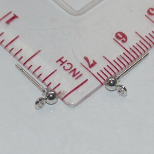 May include: Two silver earring posts with small round balls at the end. The posts are about 1 inch long and the balls are about 3/16 inch in diameter.