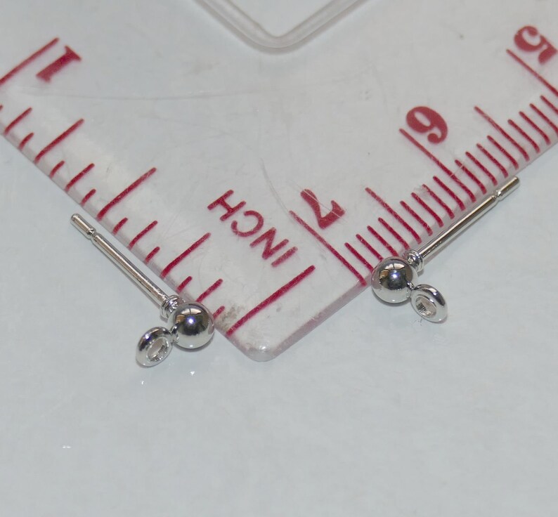 May include: Two silver earring posts with small round balls at the end. The posts are about 1 inch long and the balls are about 3/16 inch in diameter.
