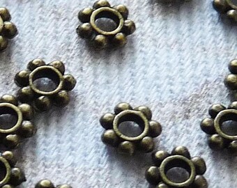May include: A close-up of a group of antique gold-toned metal spacer beads. Each bead has a circular center hole and a decorative design of small raised circles around the edge.