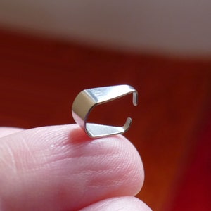 May include: A silver metal clasp for jewelry making. The clasp is open and ready to be attached to a necklace or bracelet.