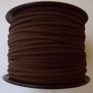 May include: A spool of brown suede cord, wound tightly on a black plastic spool.