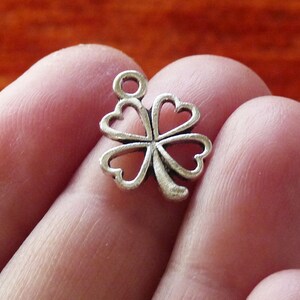 May include: Silver-toned four-leaf clover charm with a loop for attaching to a necklace or bracelet.