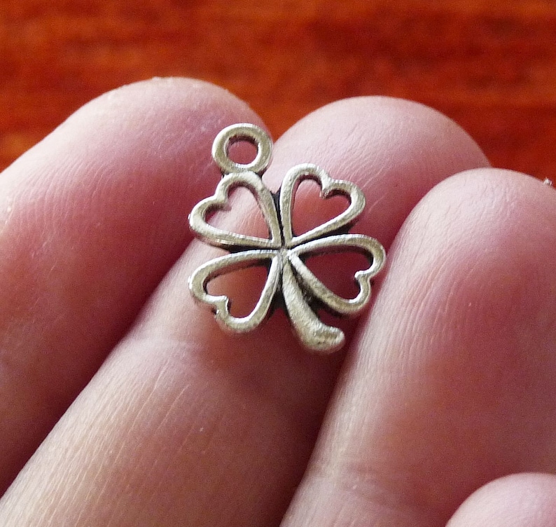 May include: Silver-toned four-leaf clover charm with a loop for attaching to a necklace or bracelet.
