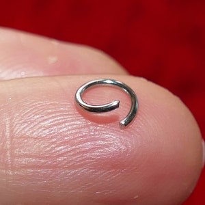 May include: A silver jump ring, a small metal ring used for connecting jewelry components.
