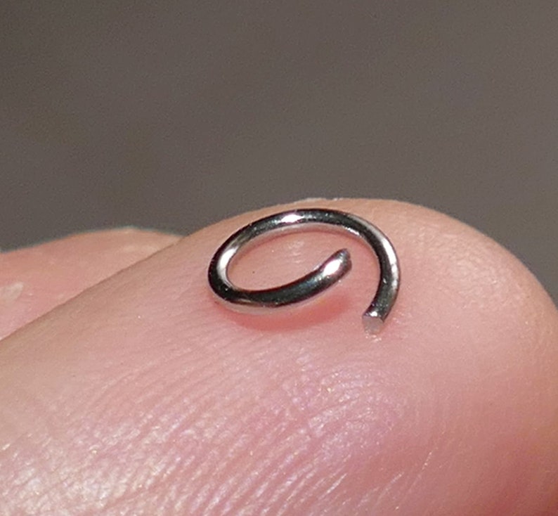 May include: A silver jump ring, a small metal ring used for connecting jewelry components.