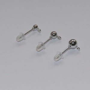May include: Three silver earring posts with clear rubber backs. The posts are different lengths.