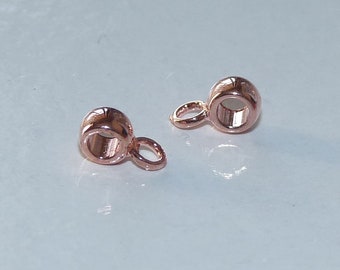 May include: Two rose gold-colored metal bead caps with a small loop on one side. The bead caps are designed to be used as a connector for jewelry making.