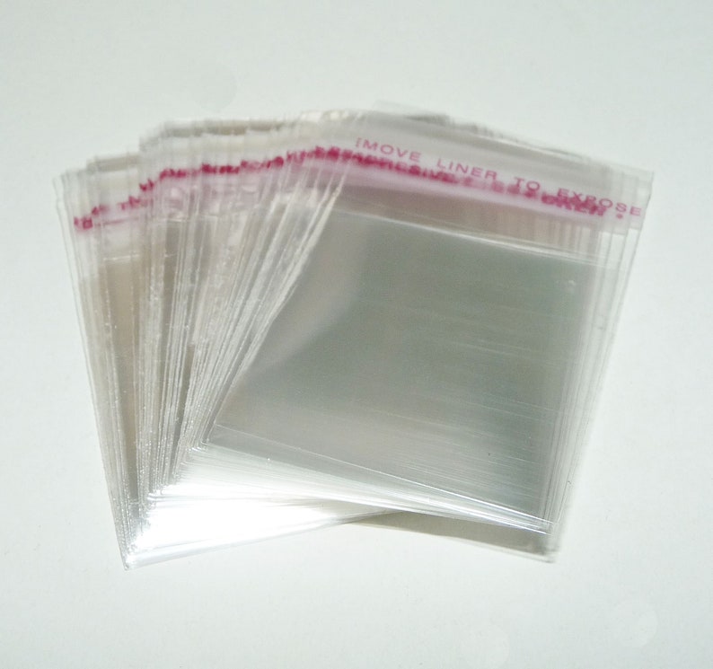 May include: A stack of clear plastic bags with a red and white adhesive strip that says "MOVE LINER TO EXPOSE".