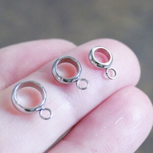 Peut inclure: Trois anneaux de saut en argent avec une petite boucle sur chaque anneau. Les anneaux sont de tailles diff&eacute;rentes.