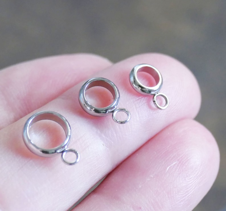 Peut inclure: Trois anneaux de saut en argent avec une petite boucle sur chaque anneau. Les anneaux sont de tailles diff&eacute;rentes.