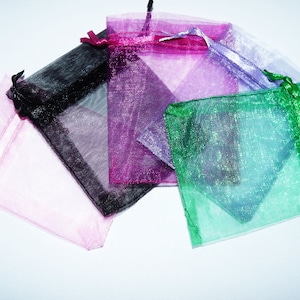 May include: Assortment of five small, sheer, colourful gift bags with drawstrings. The bags are pink, black, purple, green, and white.