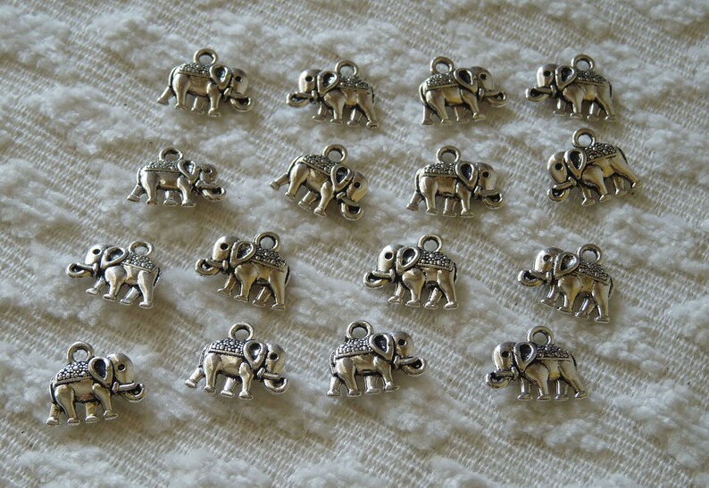 K&ouml;nnte beinhalten: Eine Sammlung von 17 silbernen Elefantenanh&auml;ngern. Die Anh&auml;nger sind mit strukturierten Oberfl&auml;chen verziert und haben oben eine &Ouml;se zum Anbringen an Schmuck oder andere Bastelarbeiten.