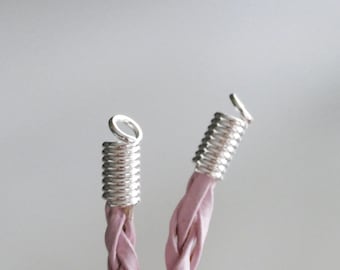 May include: Two silver metal cord ends with a loop on each end. The cord ends are attached to a pink braided cord.