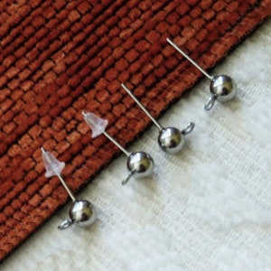 Pode incluir: Quatro postes de brincos de prata com tampas de plástico transparente e pontas de bola de prata.