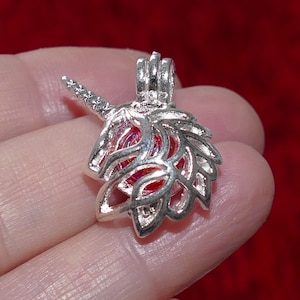 Puede incluir: Encanto de unicornio de plata con una esfera de cristal transparente en su interior. El cuerno del unicornio está curvado y el cuerpo está decorado con intrincados diseños.