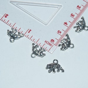 May include: Four silver bear charms with a loop for attaching to a necklace or bracelet. The charms are about 1 inch in size.