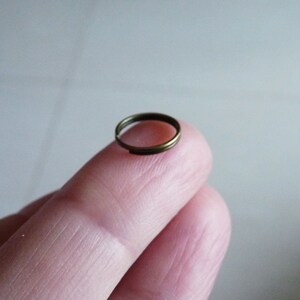 May include: A small, round, gold-coloured metal ring.