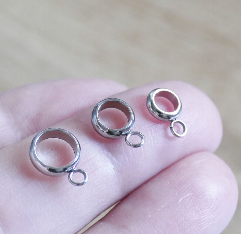 Peut inclure: Trois embouts de perles en m&eacute;tal argent&eacute; en forme d'anneau avec une petite boucle sur le c&ocirc;t&eacute;. Les embouts de perles sont sur un doigt.