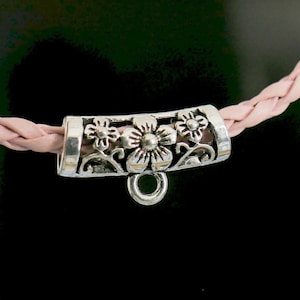 Può includere: Terminale per cordino in metallo color argento con un design floreale. Il terminale del cordino ha un anello per fissarlo a un cordino o una catena.