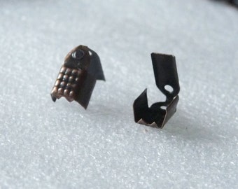May include: Two metal cord end stoppers. One is a simple, open-ended design. The other has a textured, patterned surface.
