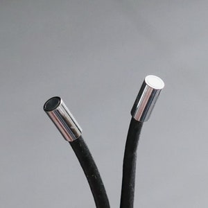 Puede incluir: Dos extremos de micrófono de metal plateado unidos a cables negros.