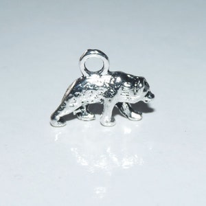 May include: Silver charm of a bear with a loop for attaching to a necklace or bracelet.