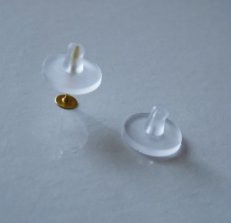 May include: Two clear plastic earring backs with a small gold post on one of the backs.