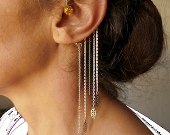 May include: A gold and silver ear cuff with multiple chains and leaf-shaped charms hanging from it.
