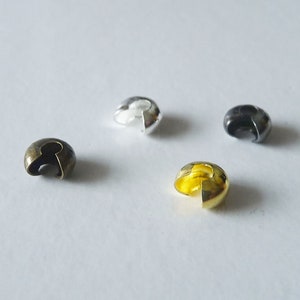 Peut inclure: Quatre perles à sertir de différentes couleurs : or, argent, bronze et noir. Ces perles sont utilisées pour fixer les extrémités des cordons ou des fils.