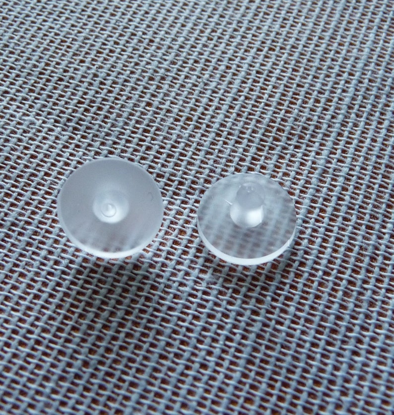May include: Two clear plastic suction cups, one with a raised center and one with a flat center.