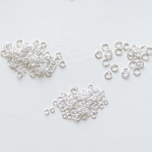May include: A pile of silver jump rings, a popular jewellery making supply, on a white background.