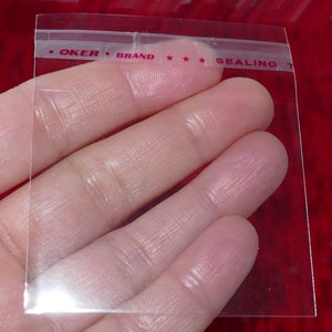 Puede incluir: Bolsa de pl&aacute;stico transparente con cierre herm&eacute;tico con una etiqueta roja y blanca que dice "OKER BRAND SEALING T".