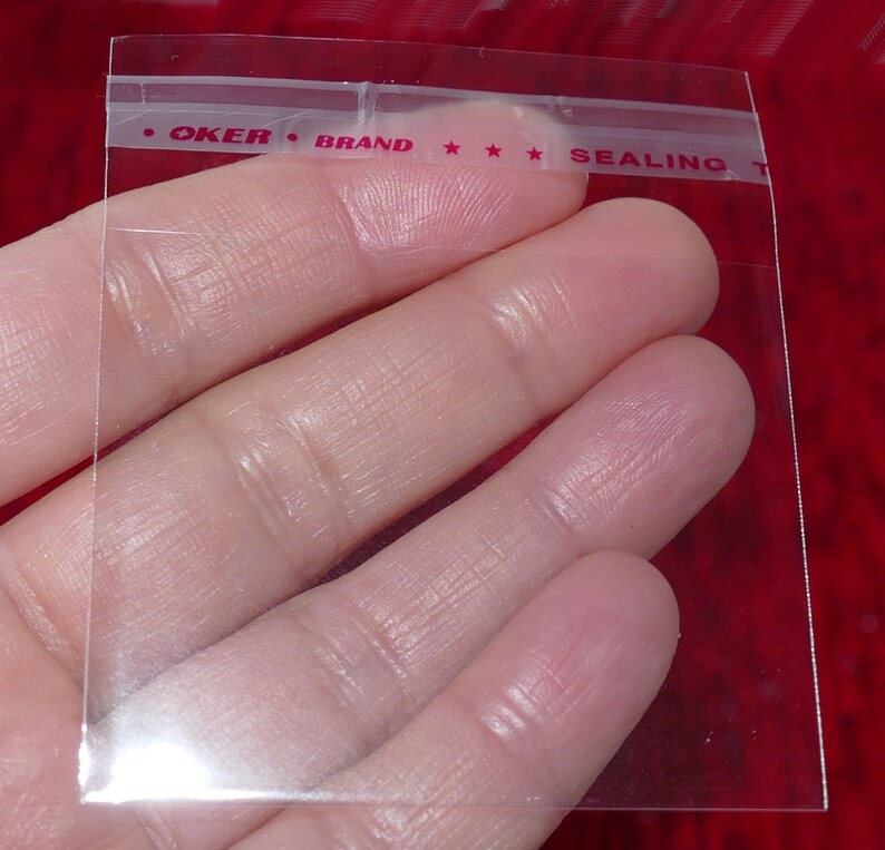 Puede incluir: Bolsa de pl&aacute;stico transparente con cierre herm&eacute;tico con una etiqueta roja y blanca que dice "OKER BRAND SEALING T".