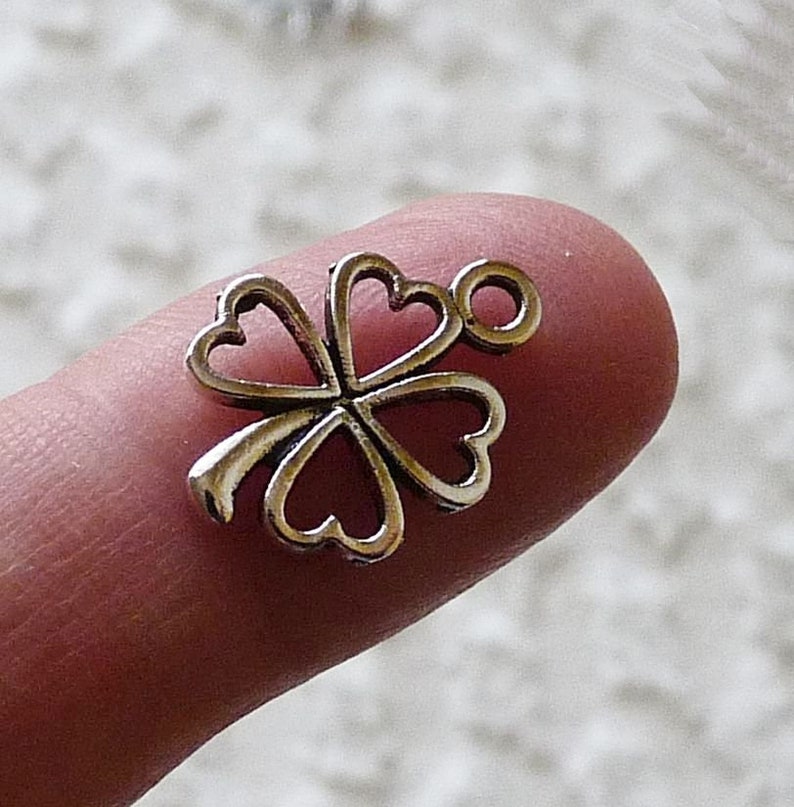 May include: Silver four-leaf clover charm with a loop for attaching to a necklace or bracelet.