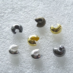 May include: Assortment of six metal crimp beads in various colors, including gold, silver, and black. The beads are designed to be used for jewelry making.