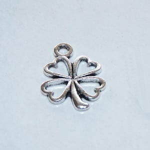 May include: Silver four-leaf clover charm with a loop at the top for attaching to a necklace or bracelet.