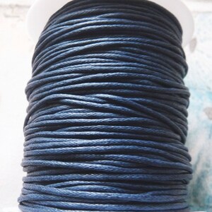 May include: A spool of dark blue waxed cotton cord. The cord is wound tightly around the spool, creating a smooth, even surface.