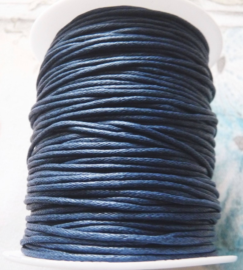 May include: A spool of dark blue waxed cotton cord. The cord is wound tightly around the spool, creating a smooth, even surface.