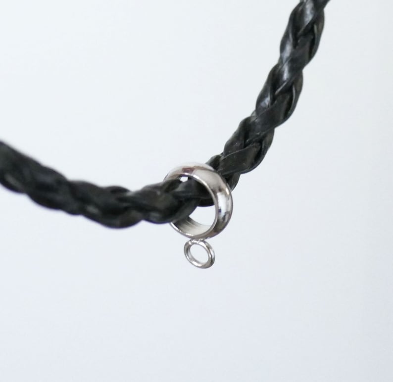 Peut inclure: Un cordon en cuir tress&eacute; noir avec une bague argent&eacute;e et une petite boucle attach&eacute;e.